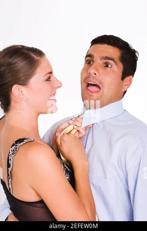 Side profile of a young woman choking a mid adult man with his tie Stock Photo