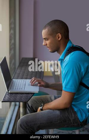 Side profile of a young man using a laptop in a cafe Stock Photo