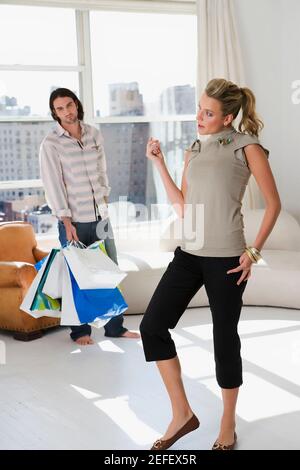 Young woman standing with a young man holding shopping bags in the background Stock Photo
