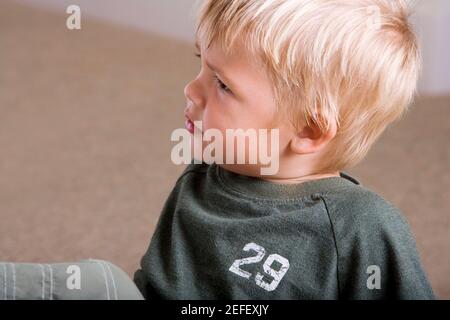 Close-up of a boy sitting on the floor Stock Photo