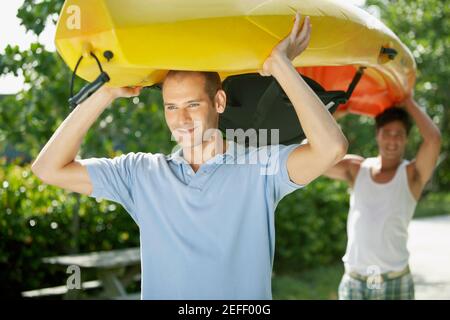 Close-up of two young men carrying a kayak over their heads Stock Photo