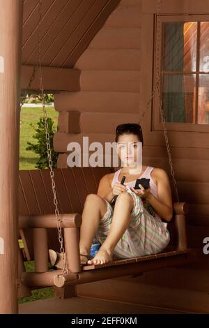 Portrait of a young woman sitting on a swing and holding a makeup brush Stock Photo