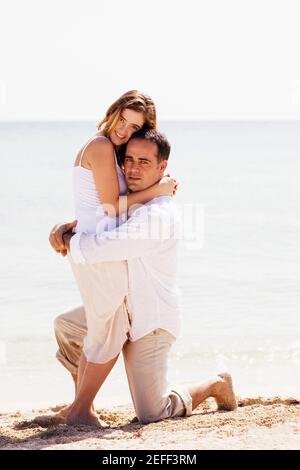 Portrait of a young woman and a mid adult man embracing each other on the beach Stock Photo