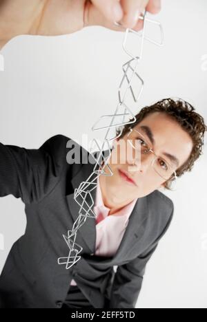 Close-up of a businessman holding a chain of paper clips Stock Photo