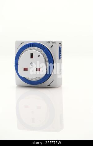 A electronic timer plug  to switch on and off lights and electrical items to a set time shot on a white background with reflection. Stock Photo