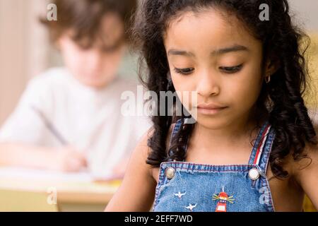 Close up of a girl looking down with a boy sitting behind her Stock Photo
