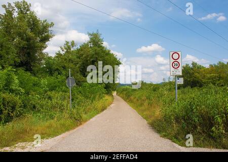 A sign on a country lane indicates that only cycles, tractors, horses and service vehicles may enter, and they must stay below 20 kph. A smaller sign Stock Photo