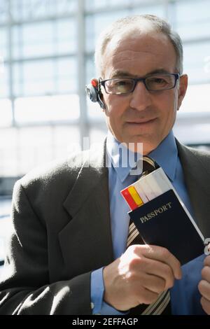 Portrait of a businessman putting a passport with an airplane ticket in his coatÅ½s pocket Stock Photo