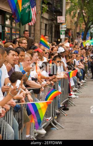 Large group of people holding gay pride flags and standing by a railing Stock Photo