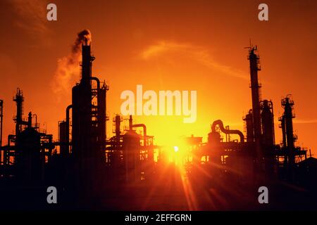 Chemical refinery plant and smokestacks in silhouette Stock Photo