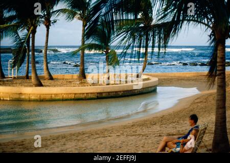 A couple is seen relaxing on a beach, Caribe Hilton, Puerto Rico Stock Photo