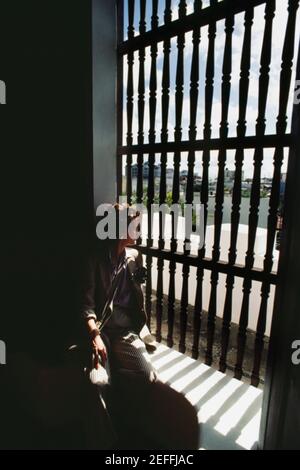 A lone woman views through a silhouetted gate, Old San Juan, Puerto Rico Stock Photo