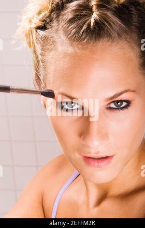 Portrait of a young woman applying eyeshadow Stock Photo