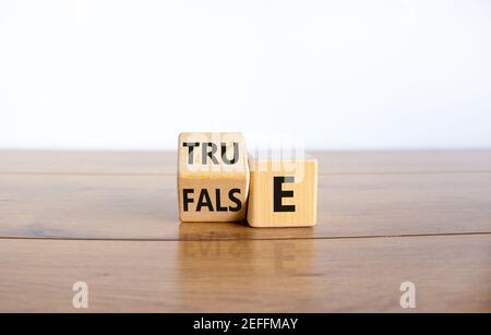 False or true symbol. Turned a wooden cube and changed the word 'false' to 'true' or vice versa. Beautiful wooden table, white background, copy space. Stock Photo