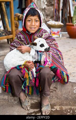 Portrait of a boy holding a lamb and smiling, Pisaq, Urubamba Valley, Peru Stock Photo