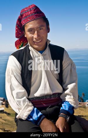 Portrait of a young man sitting and smiling, Taquile Island, Lake Titicaca, Puno, Peru Stock Photo