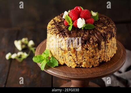 Cake Anthill decorated with raspberries, chocolate and nut on old wooden table. Selective focus. Stock Photo