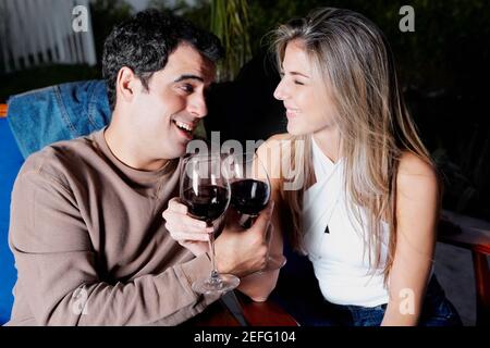 Close up of a mid adult man and a mid adult woman holding glasses of red wine and smiling Stock Photo