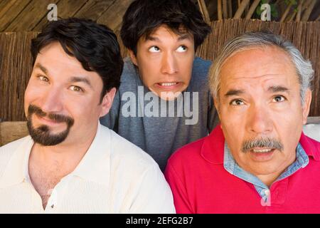 Portrait of a mid adult man smirking with his father and son making their faces Stock Photo