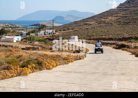 Folegandros, Greece - September 25, 2020: Man driving a quad on the road on Folegandros island. Quad is very popular means of transport in Greece. Cyc Stock Photo