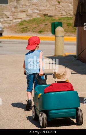 Playful young boy pulling his baby brother along in a wagon Stock Photo ...