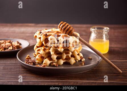 Stack of freshly homemade baked waffles on the plate with honey. Stock Photo