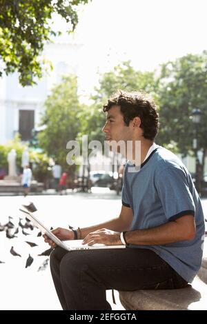 Side profile of a young man using a laptop Stock Photo