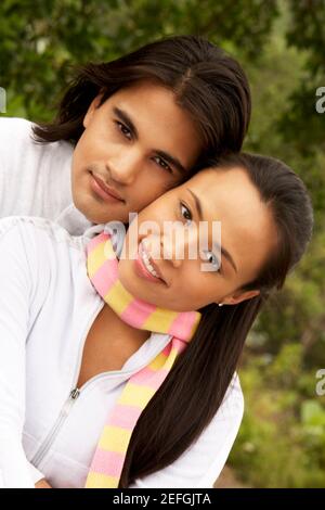 Portrait of a young man embracing a young woman from behind Stock Photo