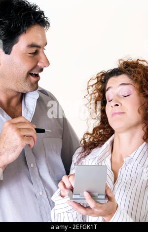 Close-up of a young woman and a mid adult man using a calculator Stock Photo