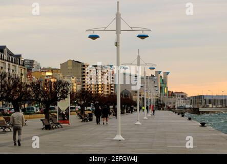 People taking early morning exercise walking along next to the bay of Santander Cantabria Spain on a windy winter morning Stock Photo