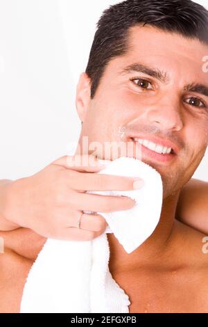 Close-up of a womanÅ½s hand wiping a mid adult manÅ½s face with a towel Stock Photo