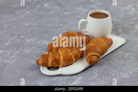 Freshly baked French croissants and cup of coffee on rustic stone table Stock Photo