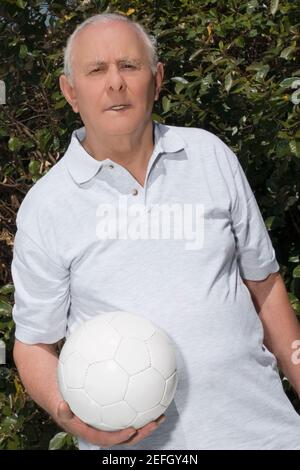 Senior man holding soccer ball in park, portrait Stock Photo - Alamy