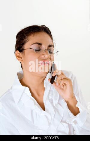 Young woman talking on a mobile phone with her eyes closed Stock