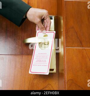 Close-up of a personÅ½s hand hanging a do not disturb sign on a door knob Stock Photo