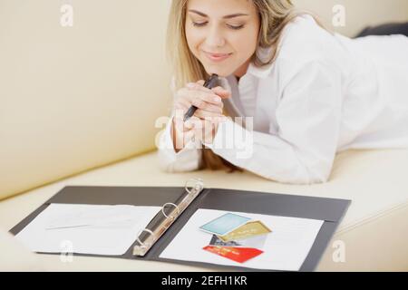 Mid adult woman lying on front on a couch and smiling Stock Photo