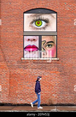 I'm watching you. A man walks beneath a window as a woman watches from above. Composite image. Stock Photo