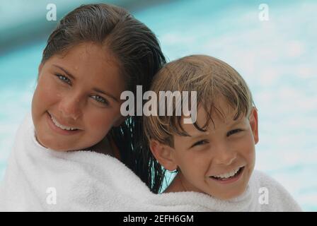 Portrait of a teenage girl and her brother wrapped in a towel and smiling Stock Photo