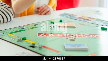 KIEL, GERMANY - 14 February 2021: Happy children having fun playing board game in cozy family time evening together with their parents Stock Photo