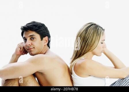 Side profile of a mid adult couple sitting back to back and looking serious Stock Photo