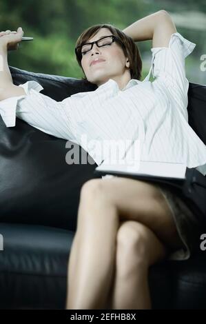 Businesswoman stretching her arms on a couch Stock Photo