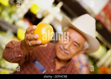 Close up of a senior man holding an orange Stock Photo