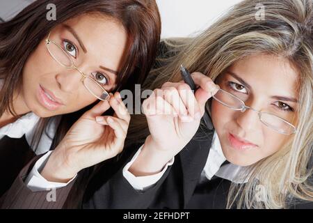 Portrait of two businesswomen holding their eyeglasses Stock Photo