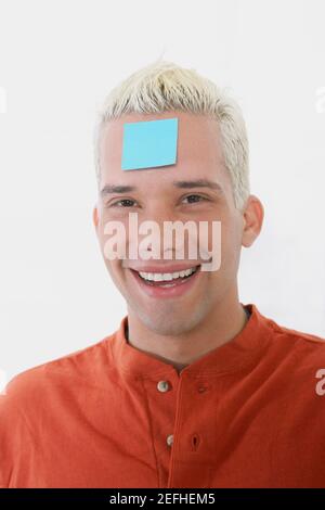 Portrait of a young man smiling with an adhesive note on his forehead Stock Photo