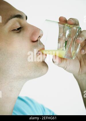 Close up of a young man drinking a glass of orange juice Stock Photo