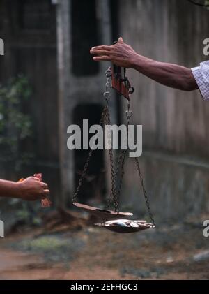 Fishermen Hand holding a scale, balancing fish and the weight, typical way of measuring the weight of fish in major parts of Sri Lanka. Stock Photo