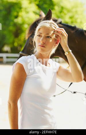 Close up of a mid adult woman standing with a horse Stock Photo