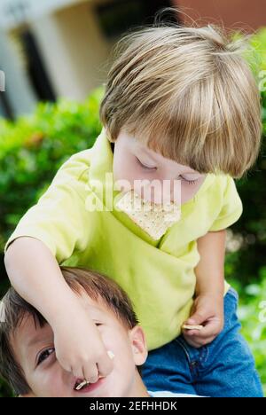 Boy feeding a biscuit to another Stock Photo