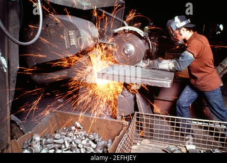 Side profile of a foundry worker working on a metal saw in a factory, Wisconsin, USA Stock Photo