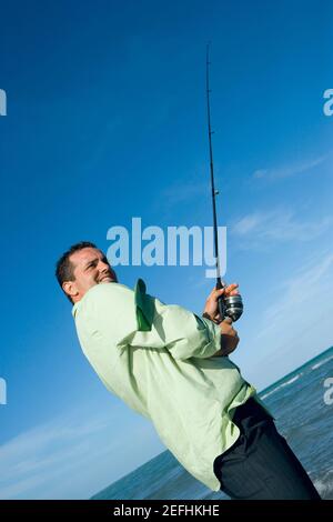 Side profile of a mid adult man holding a fishing rod on the beach Stock  Photo - Alamy